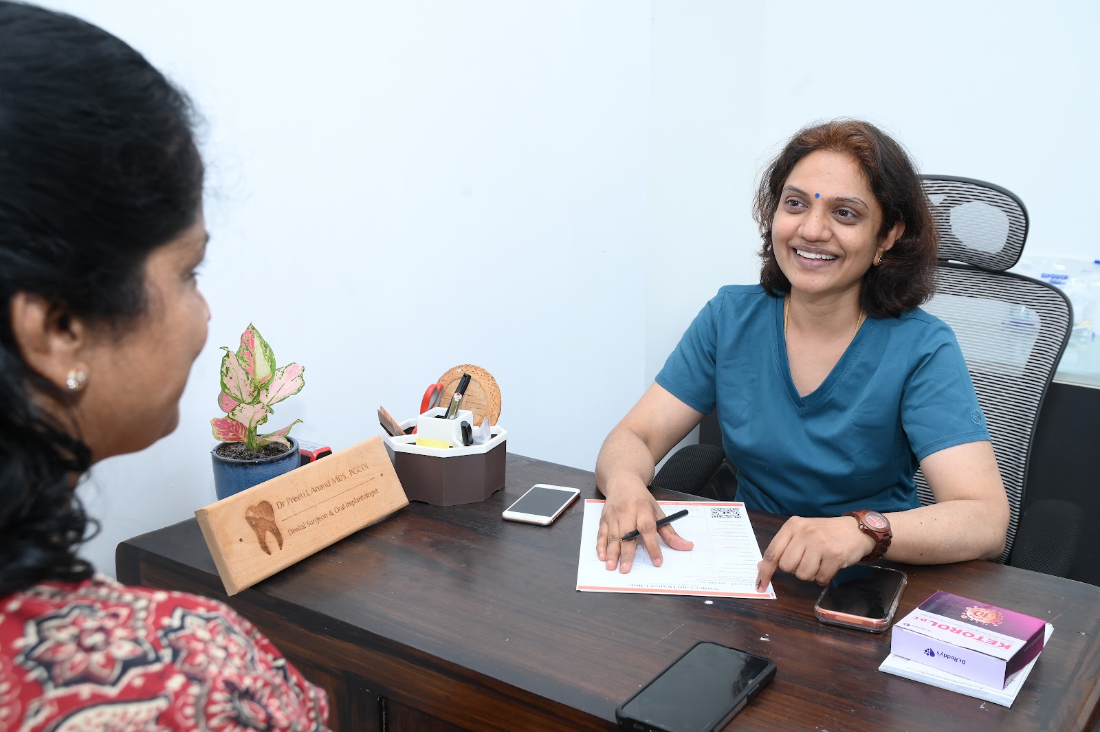 Dr. Preeti L Anand smiling with a patient at her consultation desk in Besant Nagar branch